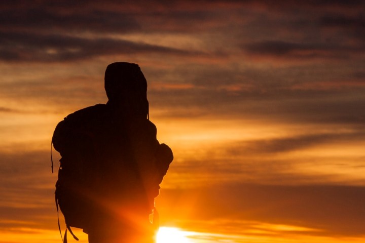 Silhouette of a person with a backpack against a vibrant sunset.